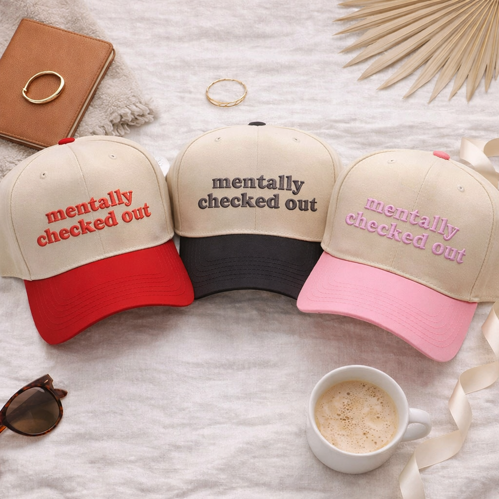 A touch of flair flat lay of a DSY Lifestyle two-tone baseball hats with a natural-colored crown and contrast bill, featuring the words Mentally Checked Out in bold corresponding embroidery.