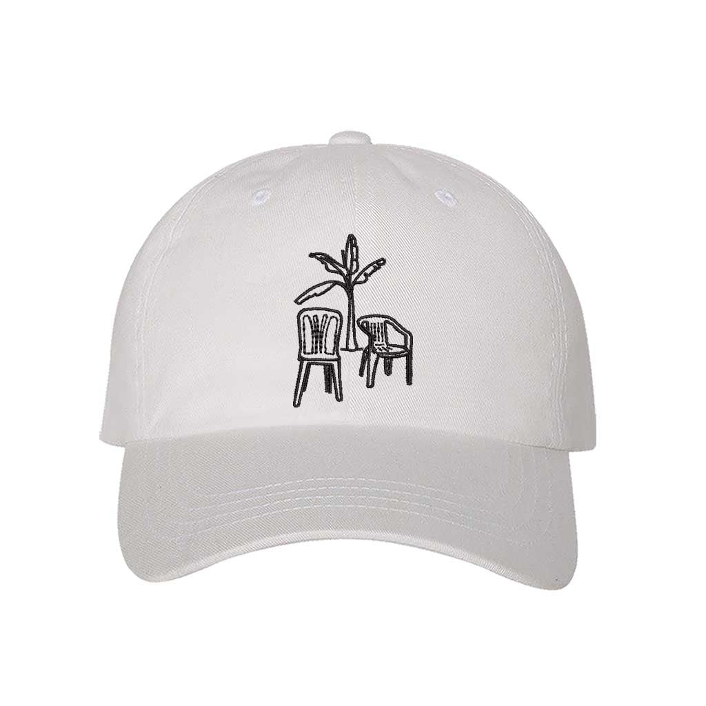 Front the DTMF Debi Tirar Mas Fotos white dad cap featuring an embroidered banana tree with two chairs, inspired by Bad Bunny&