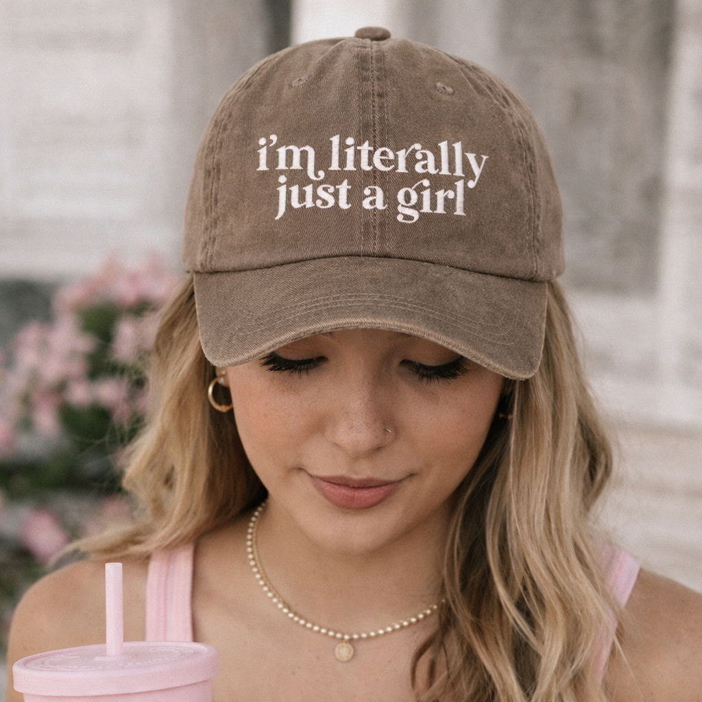 Girl in a pink pastel setting wearing a Chocolate Brown I’m Literally Just A Girl washed cotton baseball hat with a soft finish and high-density white embroidery by DSY Lifestyle. - DSY Lifestyle