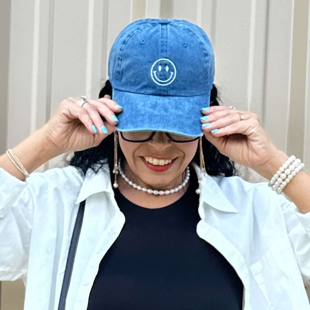 Woman wearing a navy baseball hat embroidered with a happy face