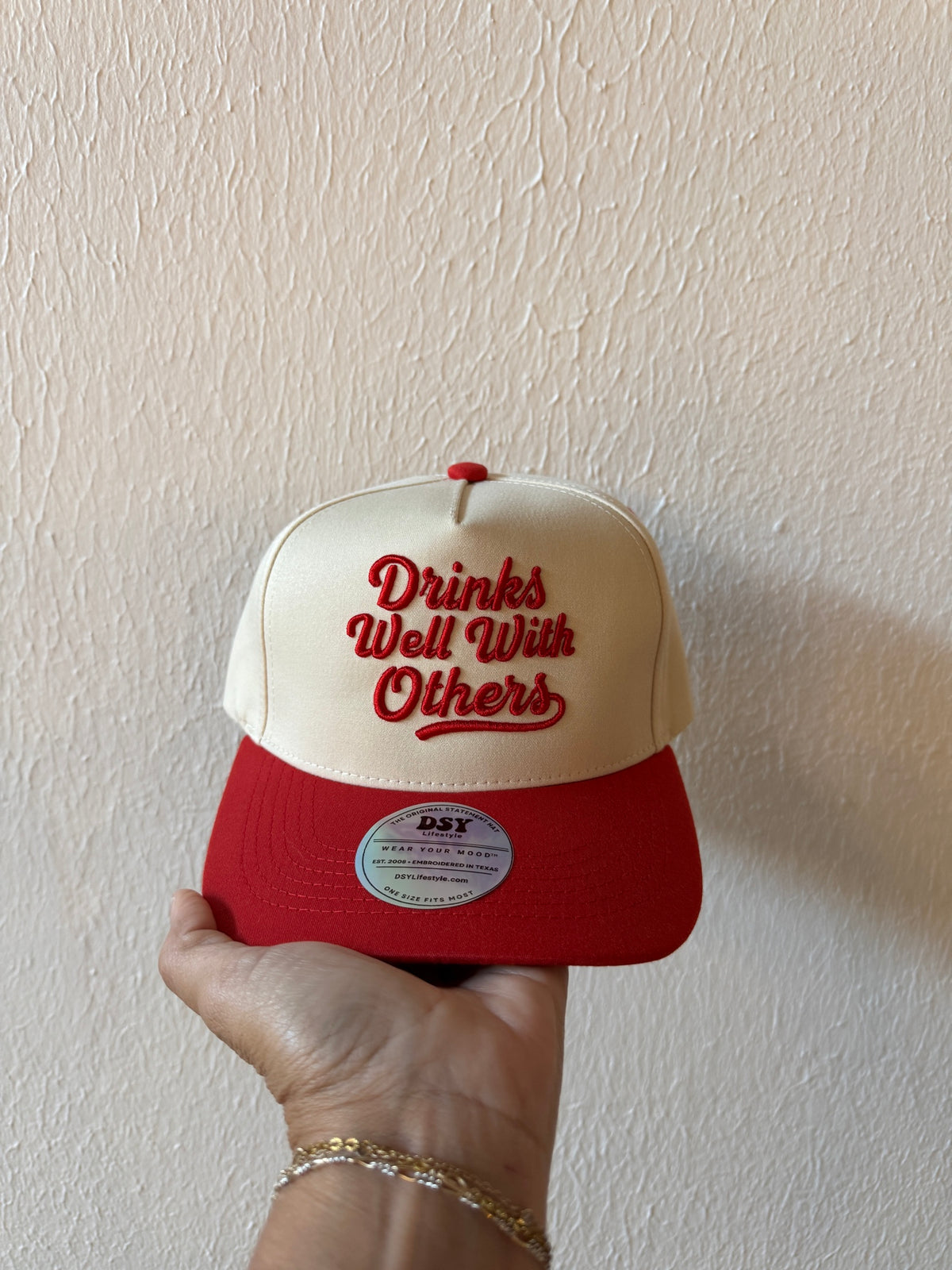 Drinks Well With Others embroidered two-tone trucker hat on a white background