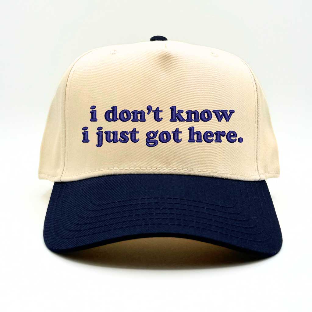 Natural baseball hat with navy colored bill and the phrase i don&