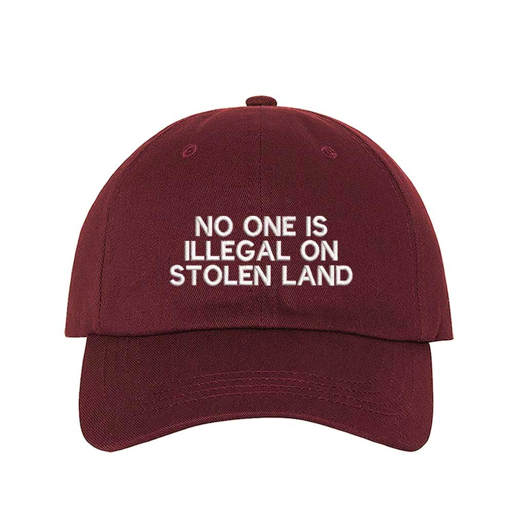 Burgundy No One Is Illegal On Stolen Land Baseball Hat featuring bold white embroidery on a classic cotton dad cap; a powerful social justice statement piece by DSY Lifestyle.