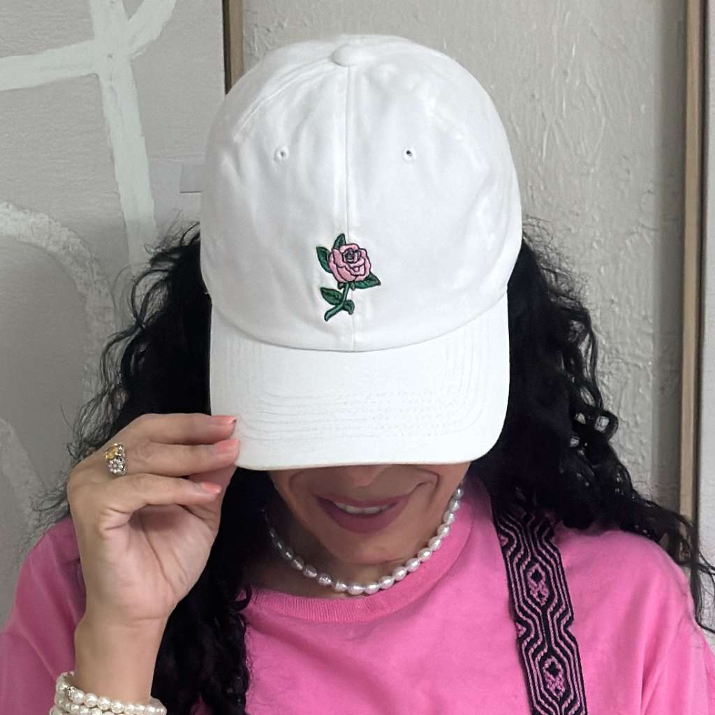 Female wearing a white baseball cap embroidered with a pink rose