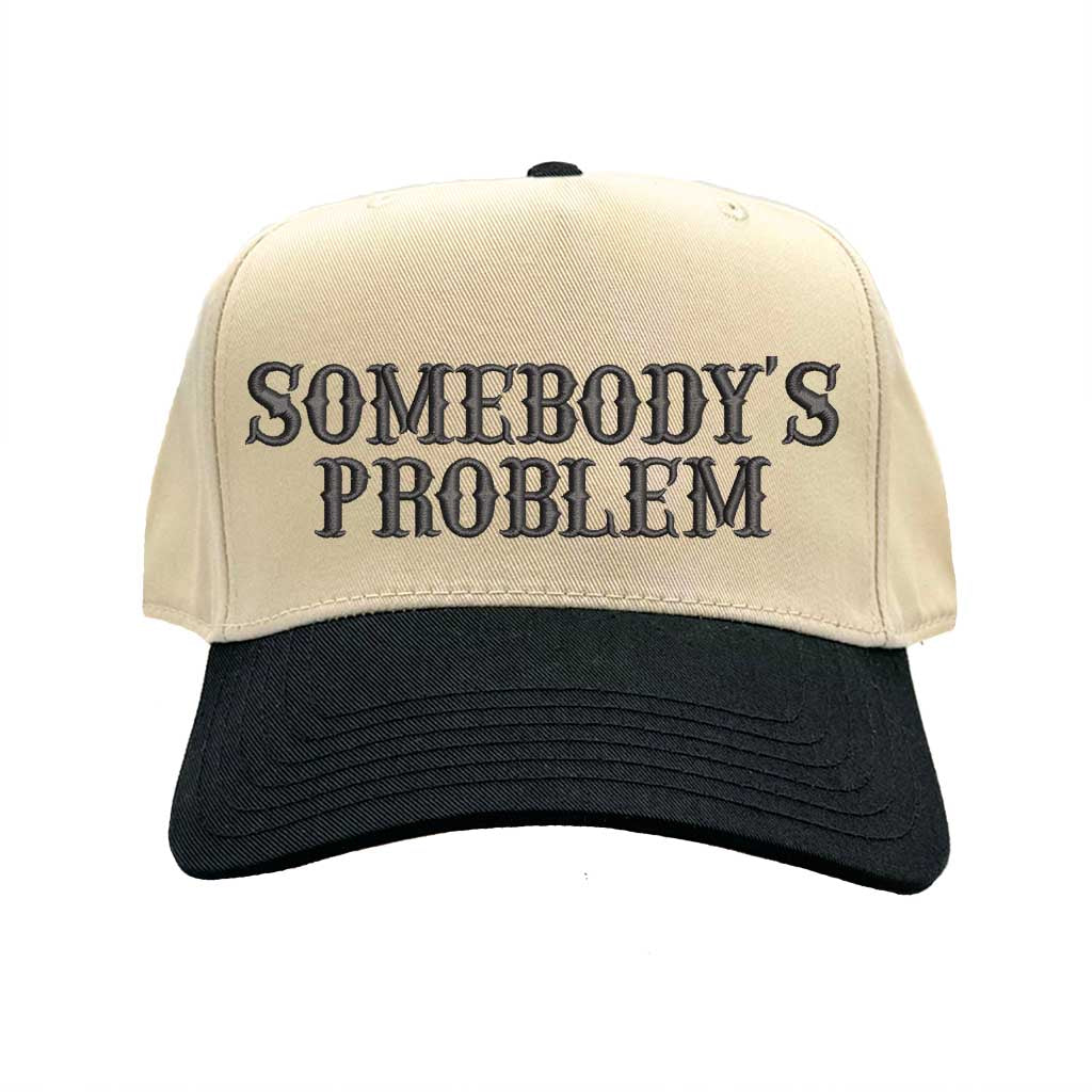 Natural Black two-tone 5 panel Somebody’s Problem embroidered dad hat with white front panel, beige brim, bold black text, and adjustable strap. – DSY Lifestyle.