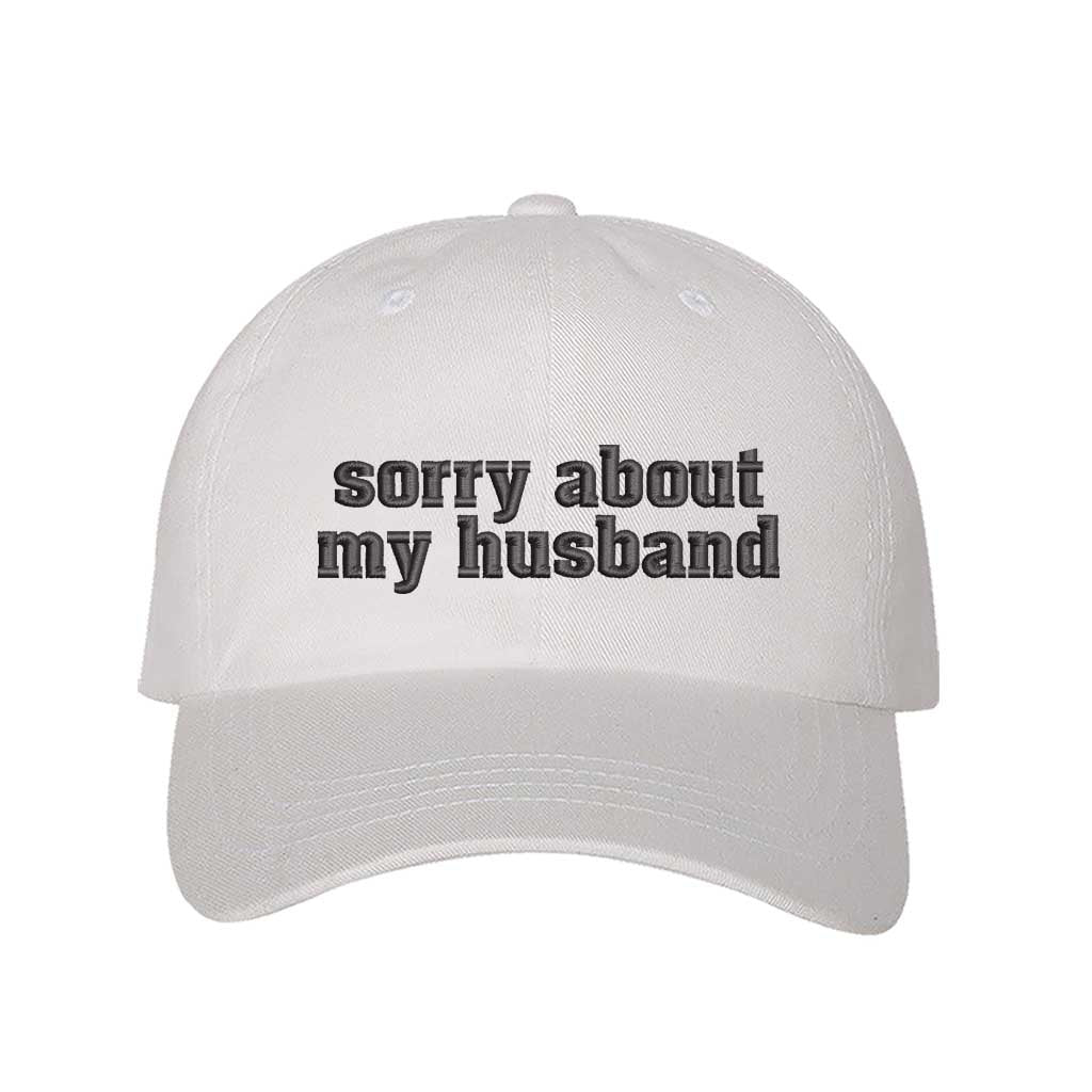 White Sorry About My Husband Embroidered Baseball Hat in classic cotton dad cap style with curved brim and hook and loop closure. DSY Lifestyle.