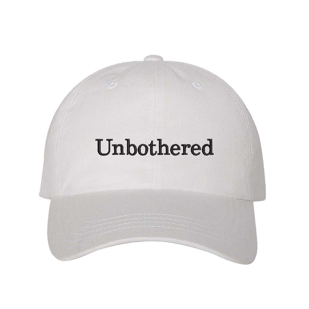 White Front view of a classic baseball hat featuring "Unbothered" in high-density black script embroidery on the center crown. - DSY Lifestyle