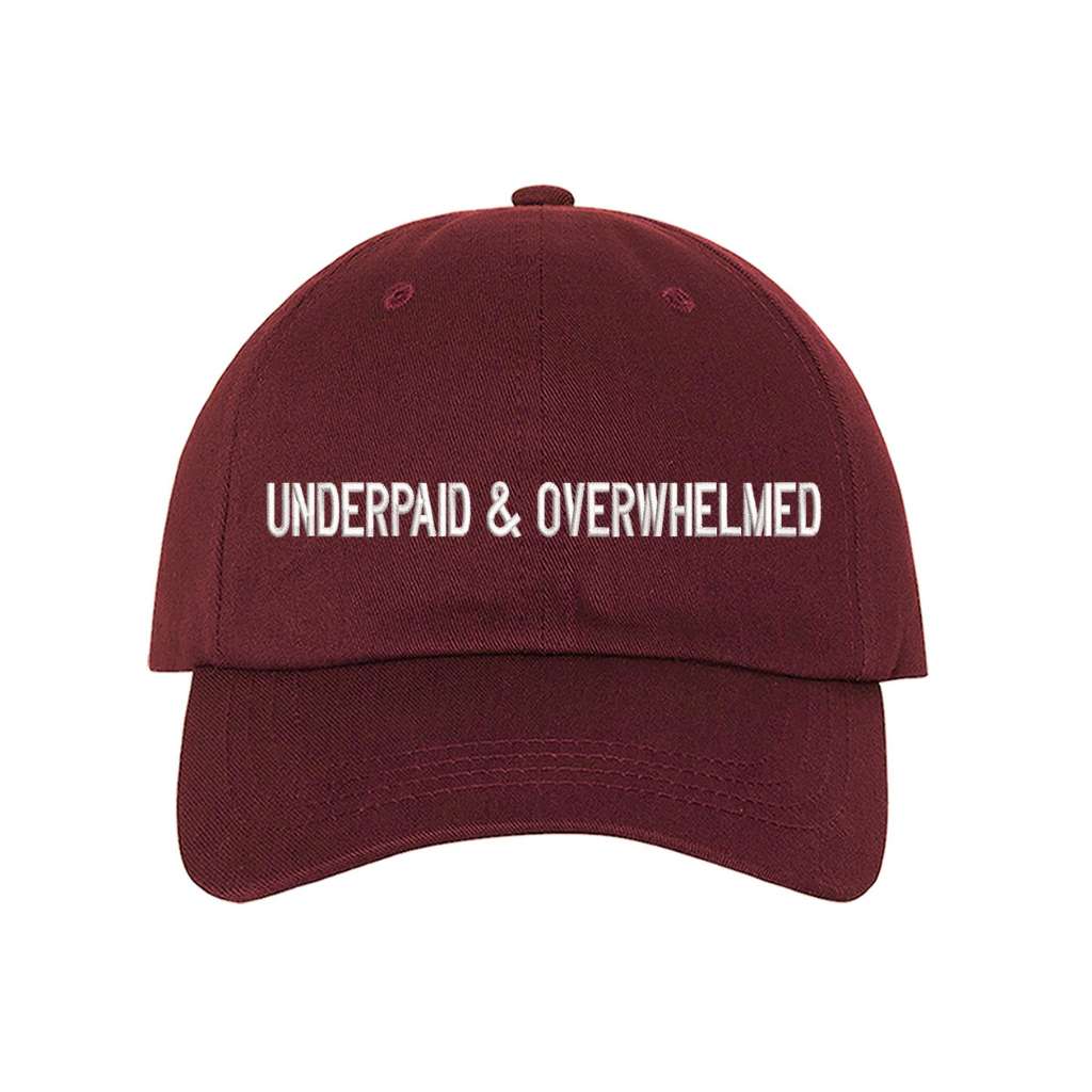Burgundy baseball hat with the phrase underpaid & overwhelmed embroidered on it-DSY Lifestyle