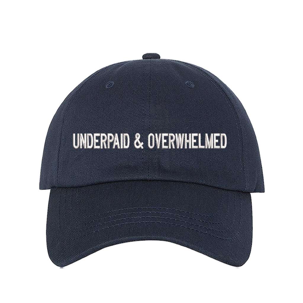 Navy blue baseball hat with the phrase underpaid & overwhelmed embroidered on it-DSY Lifestyle