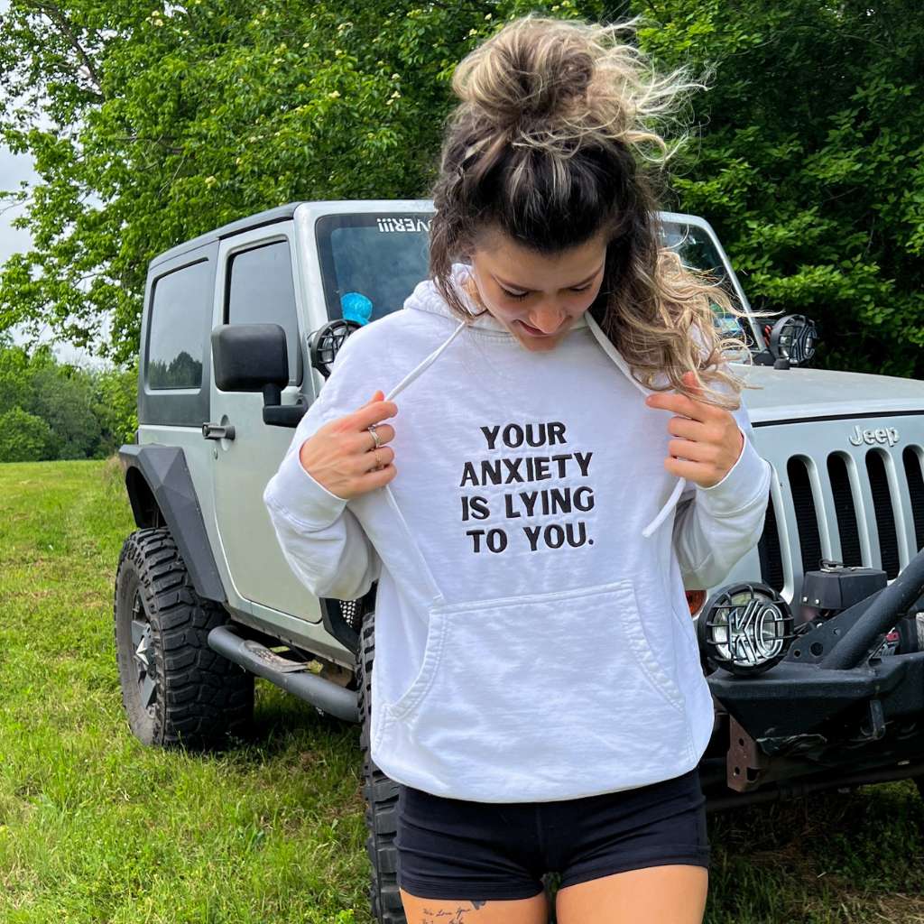 Female wearing a white hoodie embroidered with Your anxiety is lying to you - DSY Lifestyle