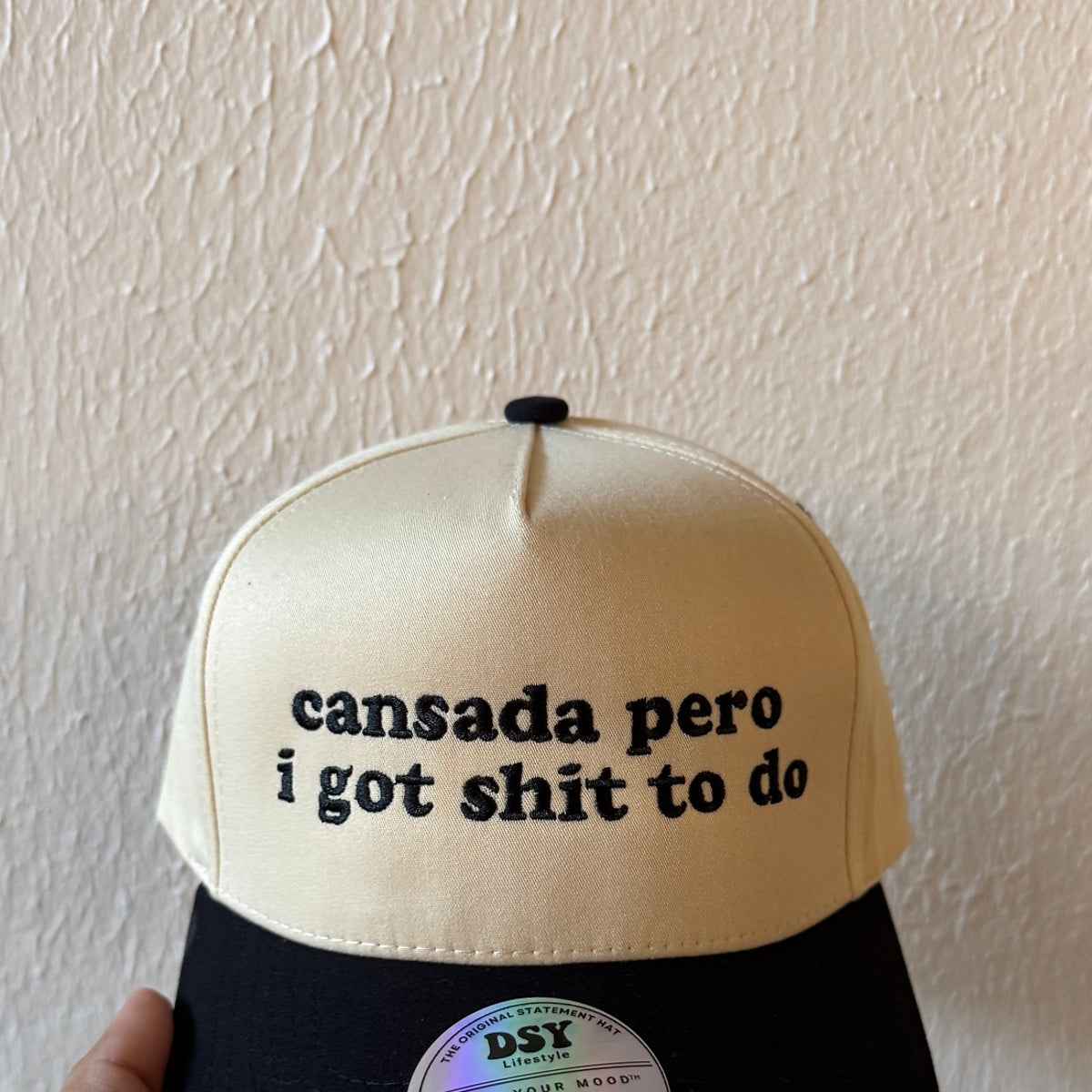 Close-up of Cansada Pero I Got Shit to Do machine embroidery on a two-tone trucker hat