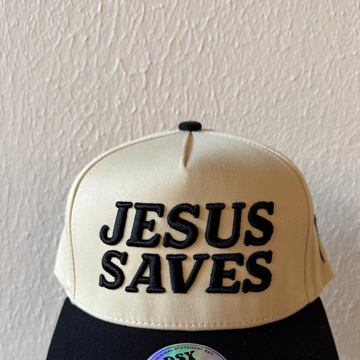 Close-up of Jesus Saves machine embroidery on a two-tone trucker hat