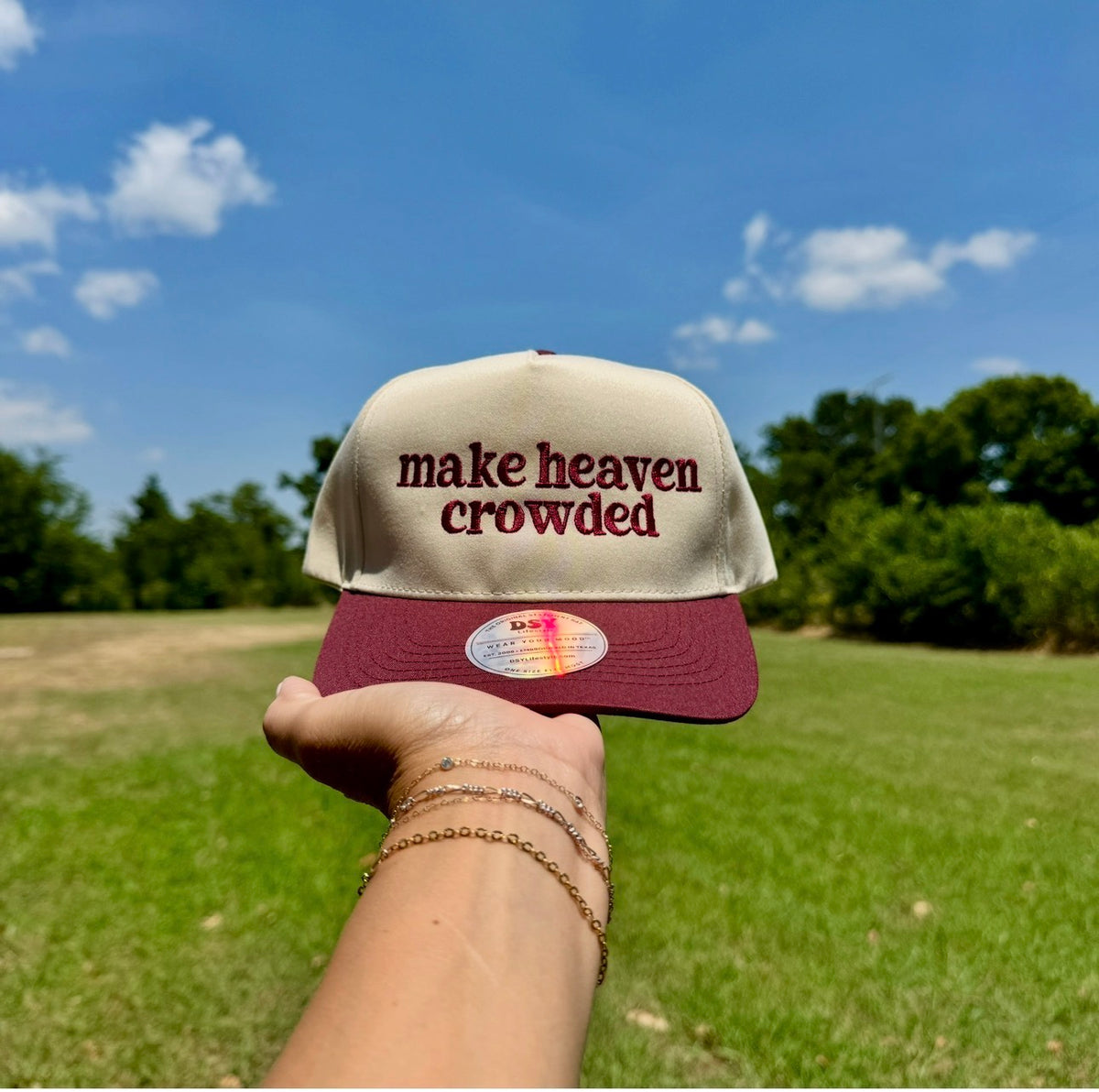 Make heaven crowded embroidered trucker hat with a maroon bill held outdoors