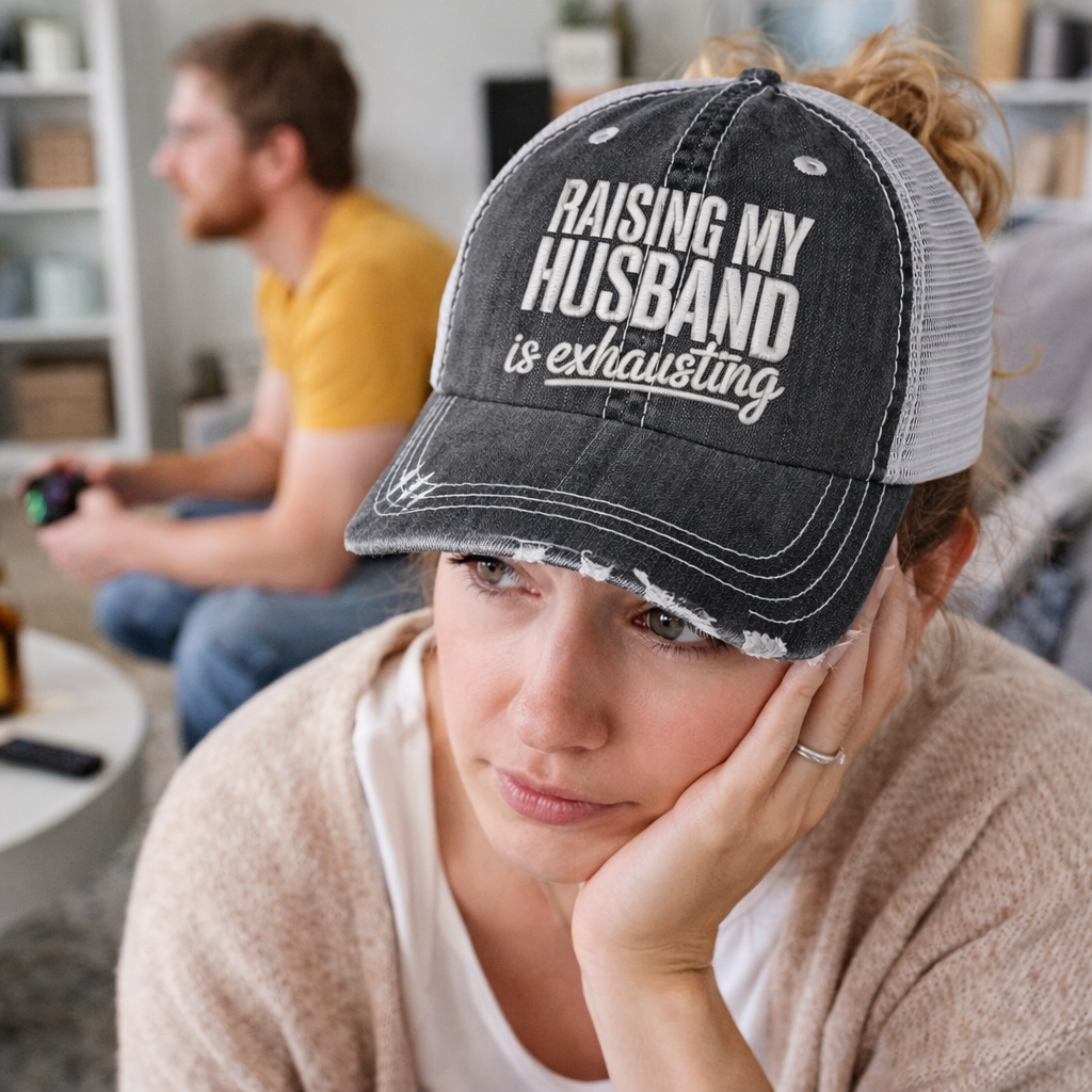 Female looking exhausted wearing a Black DSY Lifestyle distressed trucker hat featuring the phrase Raising My Husband Is Exhausting in bold, professional embroidery. - DSY Lifestyle