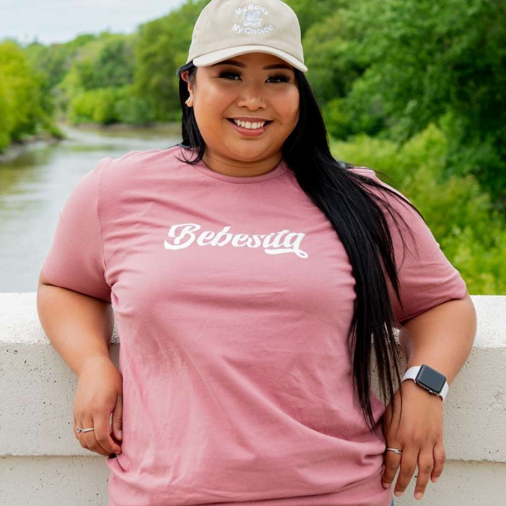 Female wearing stone color baseball hat and a Mauve T-shirt with Bebesita printed in the front- DSY Lifestyle