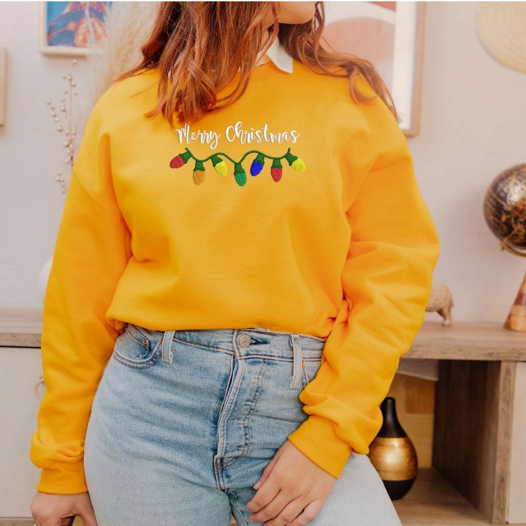 Female wearing a Gold crewneck sweatshirt embroidered with Merry Christmas in the front- DSY Lifestyle