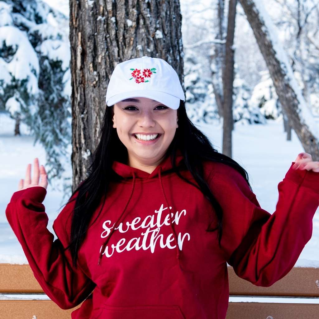 Female wearing a white baseball hat embroidered with poinsettias - DSY Lifestyle