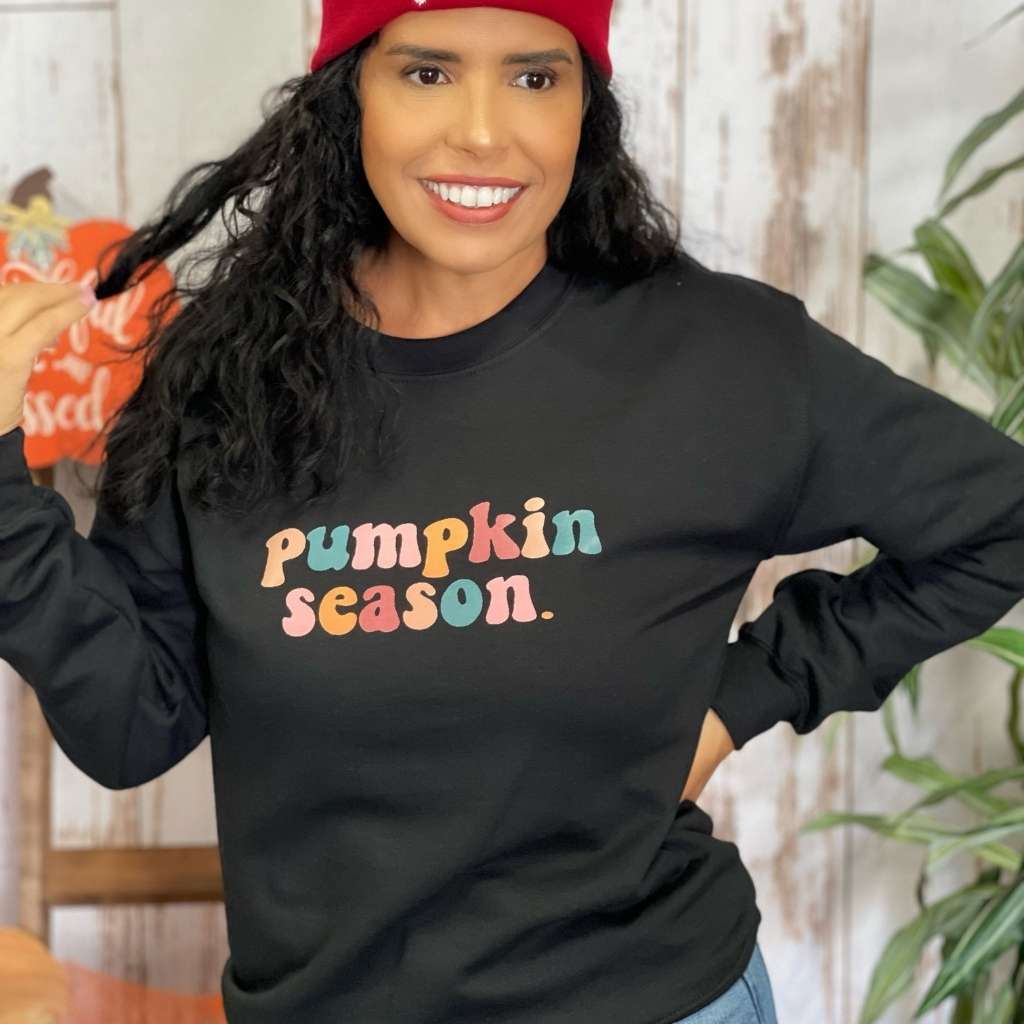 Female wearing a black crewneck sweatshirt printed with pumpkin season in the front - DSY Lifestyle