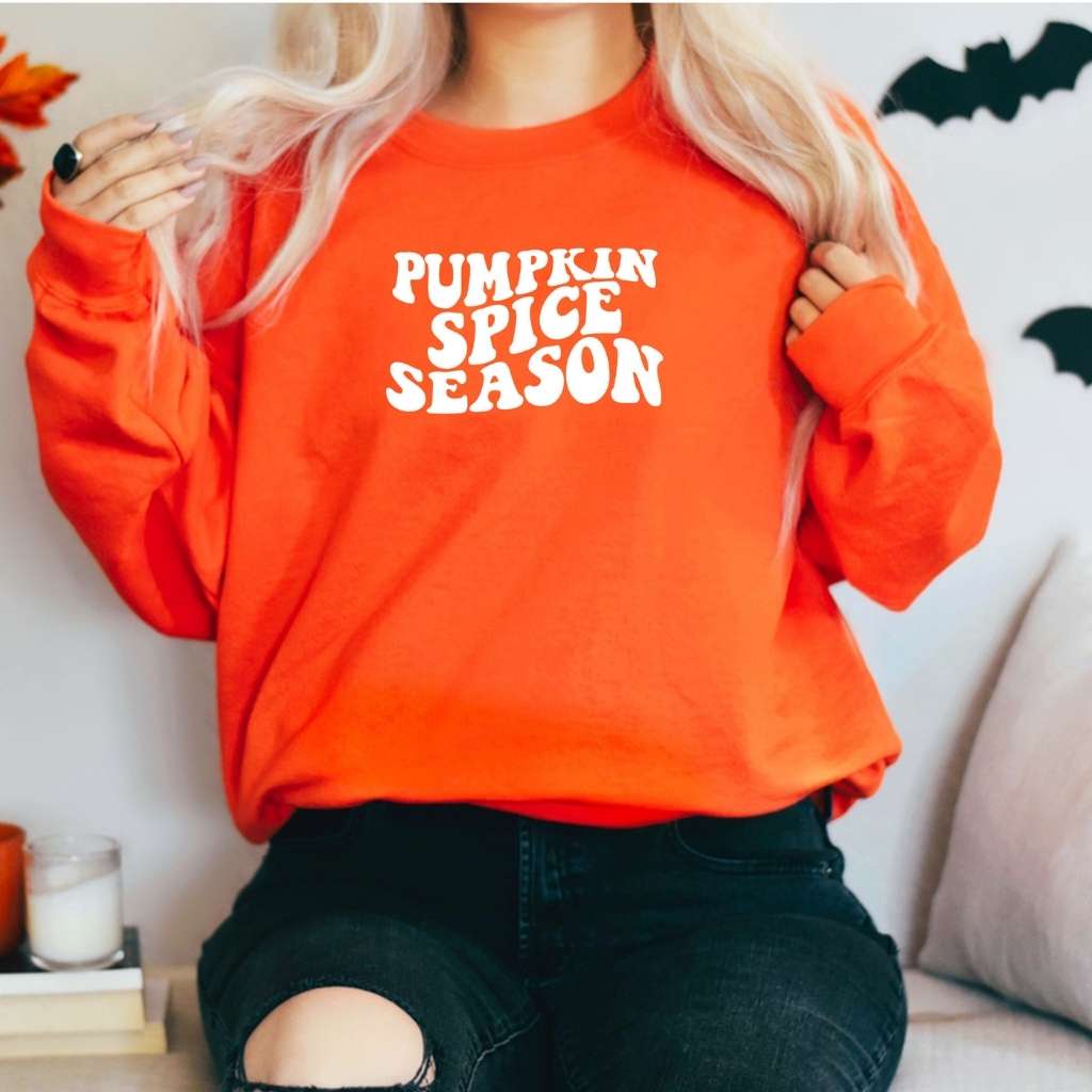 Female wearing a orange Unisex orange sweatshirt with pumpkin spice sprinted in the front in white - DSY Lifestyle