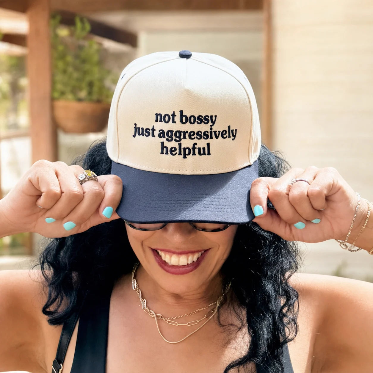 Daisy wearing a cream and navy trucker hat embroidered Not Bossy Just Aggressively Helpful
