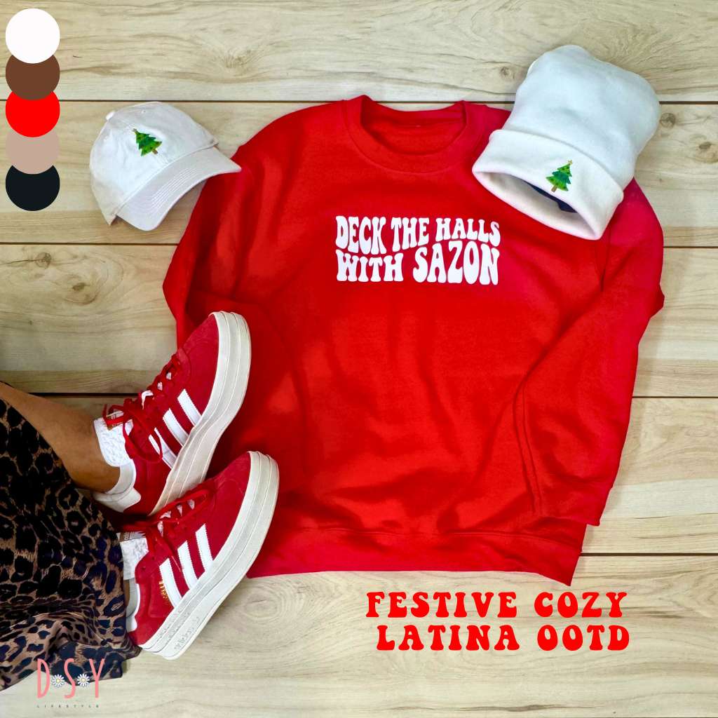 pinterest flay lay of festive latina ootd featuring a red sweatshirt with deck the halls with sazon and a white baseball cap with a christmas tree embroidered and a white beanie with a xmas tree embroidered 