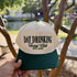 Day Drinking Social Club trucker hat in Natural / Forest Green Bill with forest green lettering, held up by a lake