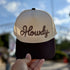 Howdy Rope trucker hat in Natural / Brown Bill with brown rope-style Howdy script embroidery, held up outdoors