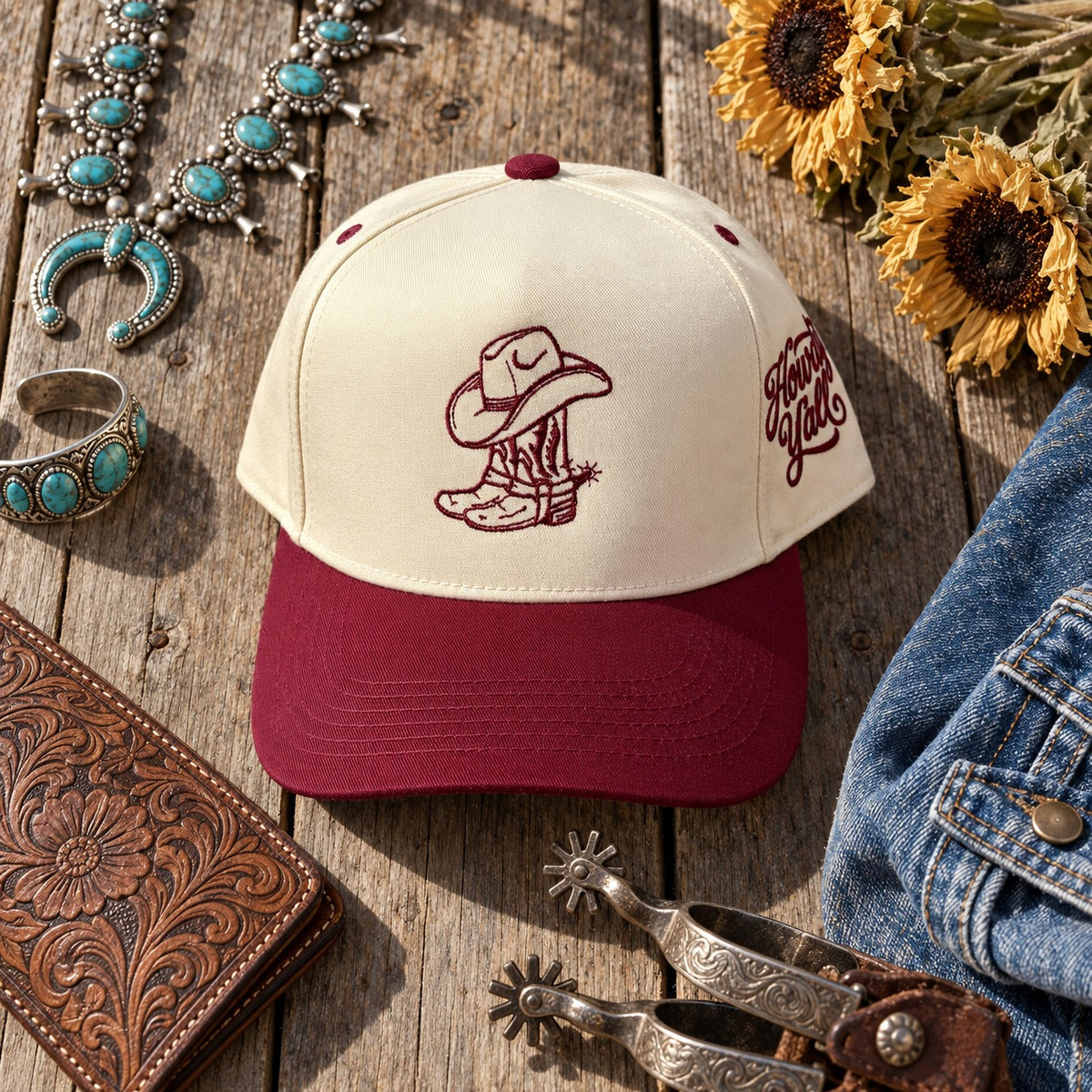 Cowgirl Boots Howdy Yall trucker hat flat lay on porch boards with turquoise jewelry, sunflowers, a tooled leather wallet, spurs, and a denim jacket