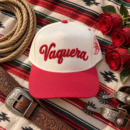 Vaquera trucker hat flat lay on a serape with a lasso, red roses, a tooled leather belt, and spurs