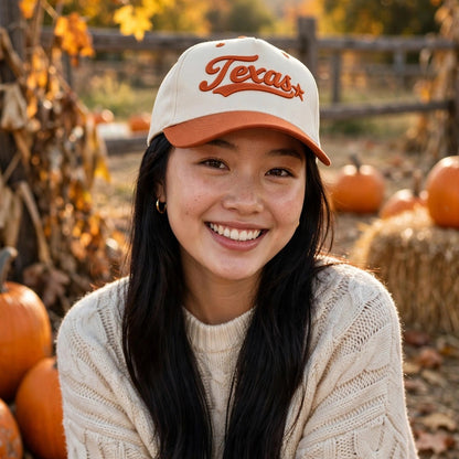 Woman at a fall pumpkin patch wearing the Texas 3D Star trucker hat in Natural / Orange Bill with matching orange embroidery