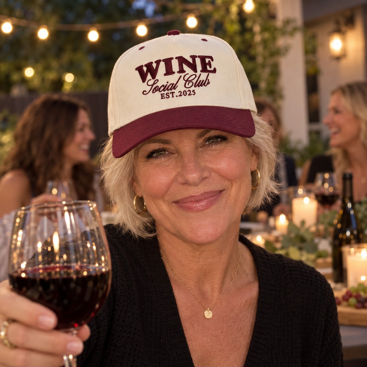 Woman at a patio wine night wearing the Wine Social Club trucker hat in Natural / Maroon Bill with maroon embroidery