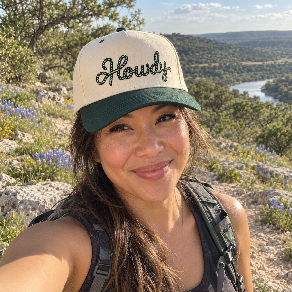 Woman on a Hill Country hiking trail wearing the Howdy Rope trucker hat in Natural / Forest Green Bill with forest green embroidery