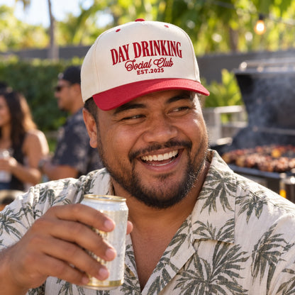 Man at a backyard barbecue wearing the Day Drinking Social Club trucker hat in Natural / Red Bill with red embroidery