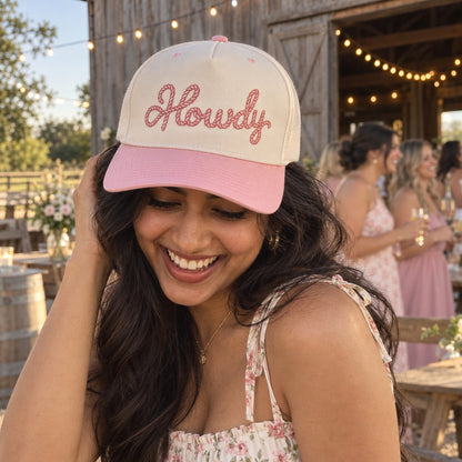 Woman at a barn venue with string lights wearing the Howdy Rope trucker hat in Natural / Pink Bill with pink embroidery