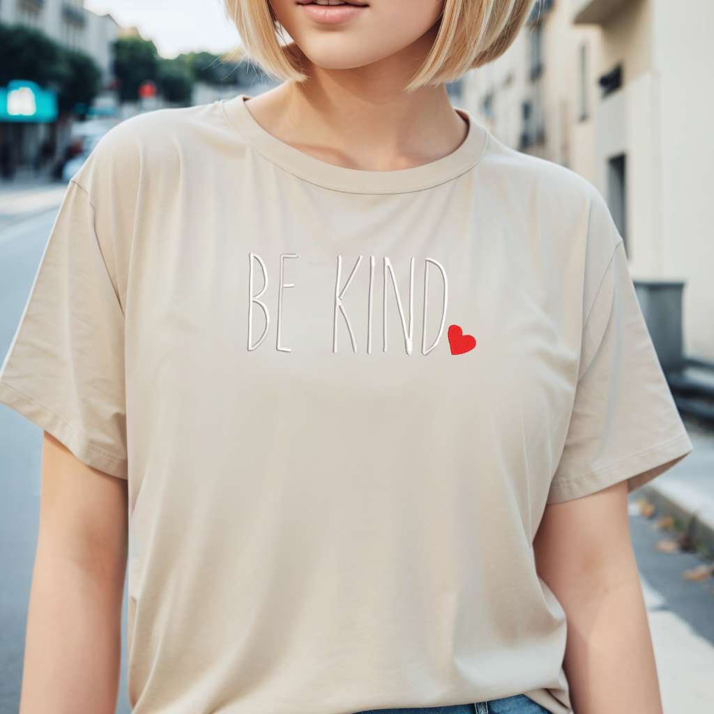 Female wearing a sand oversized unisex t-shirt embroidered with Be Kind and a heart - DSY Lifestyle