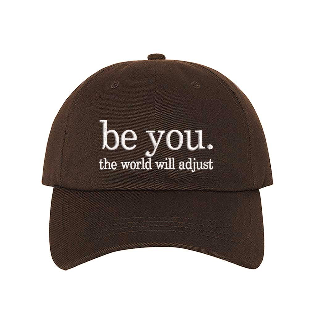 Brown Be You The World Will Adjust embroidered baseball hat featuring clean minimalist typography and professional stitching by DSY Lifestyle.