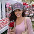 Cute female in flower shop wearing a Gray Candy Hearts Washed Baseball Hat featuring colorful pastel conversation heart embroidery on a vintage washed dad cap by DSY Lifestyle.