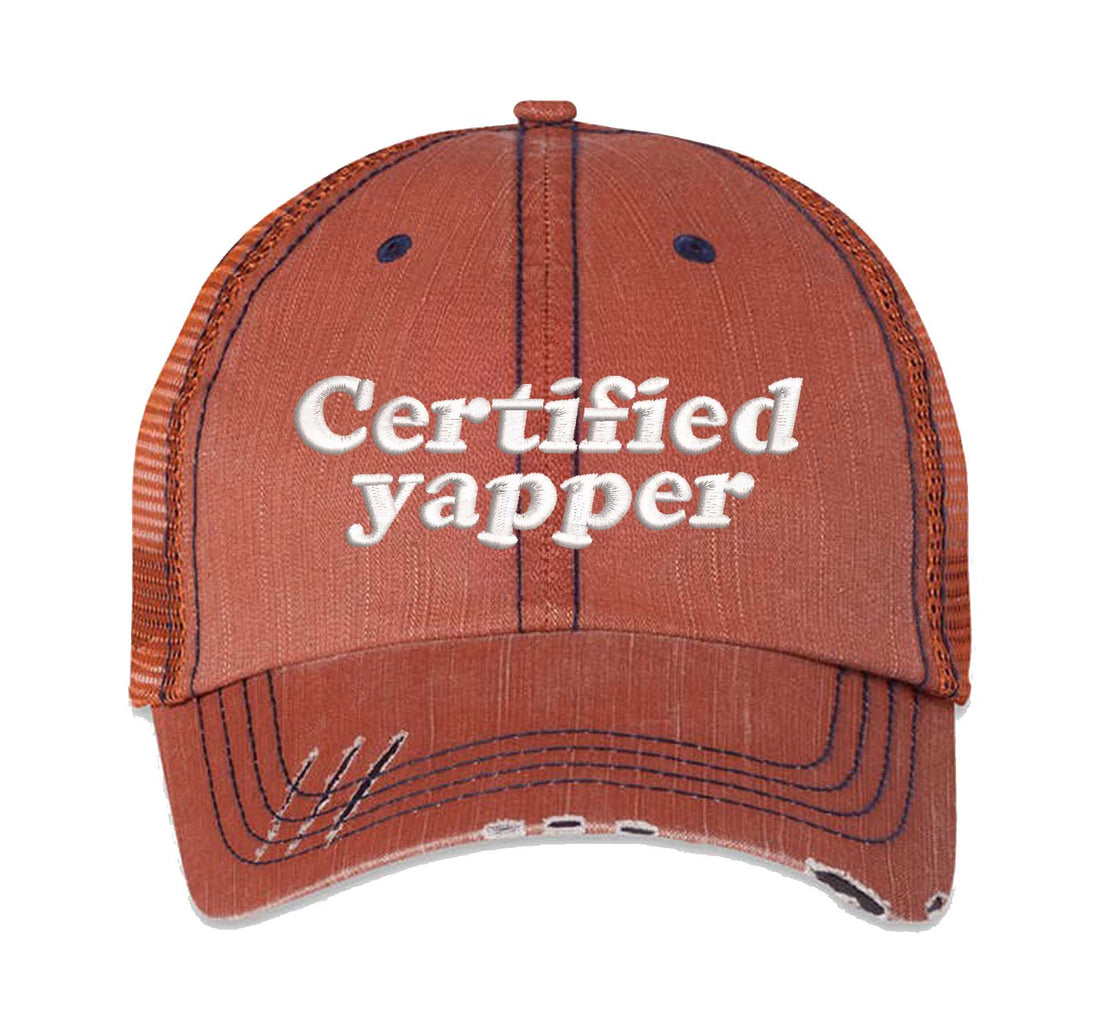 Orange DSY Lifestyle distressed trucker hat featuring the phrase Certified Yapper in bold, professional embroidery. - DSY Lifestyle