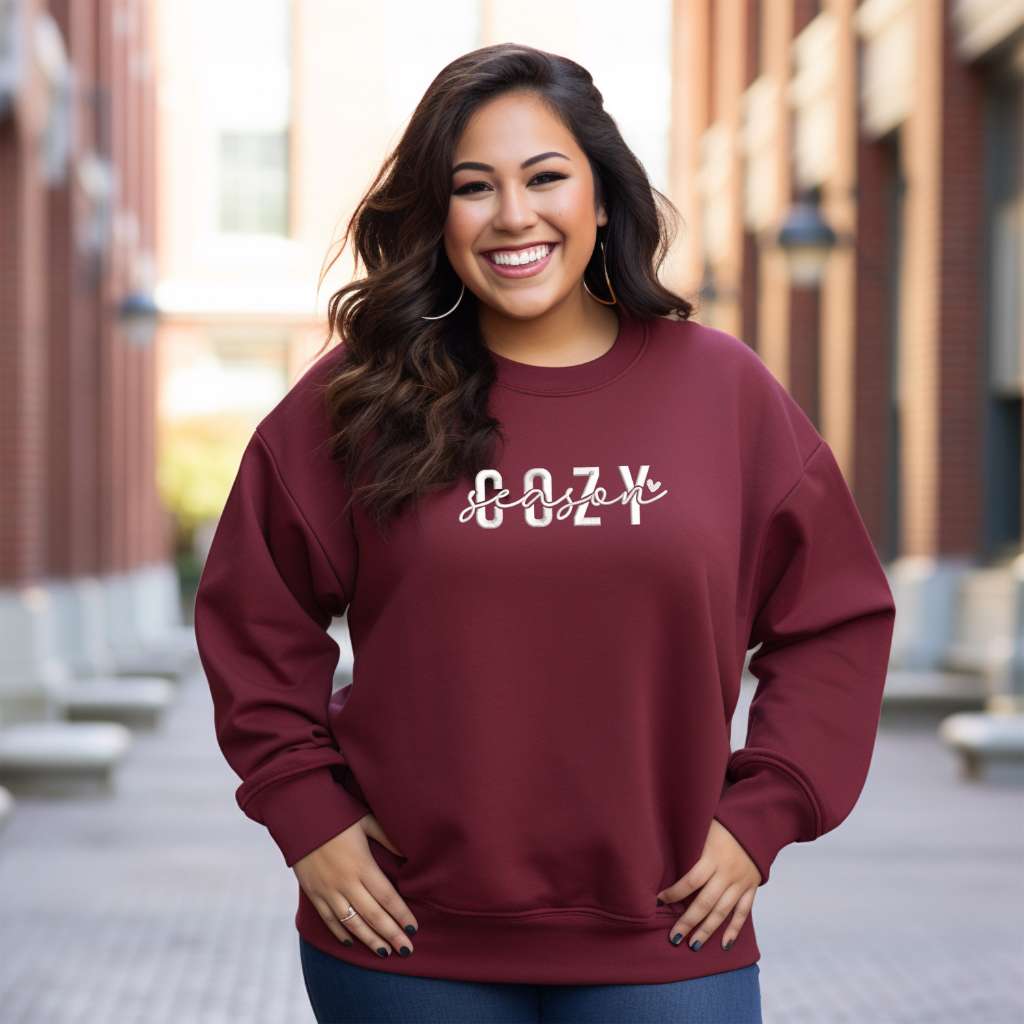 Female wearing a burgundy crewneck sweatshirt embroidered with Cozy Season - DSY Lifestyle