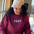 Female wearing a burgundy crewneck sweatshirt embroidered with Cozy Season - DSY Lifestyle
