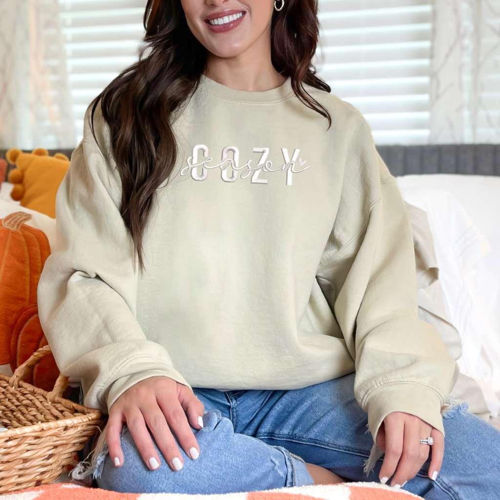 Female wearing a sand crewneck sweatshirt embroidered with Cozy Season - DSY Lifestyle