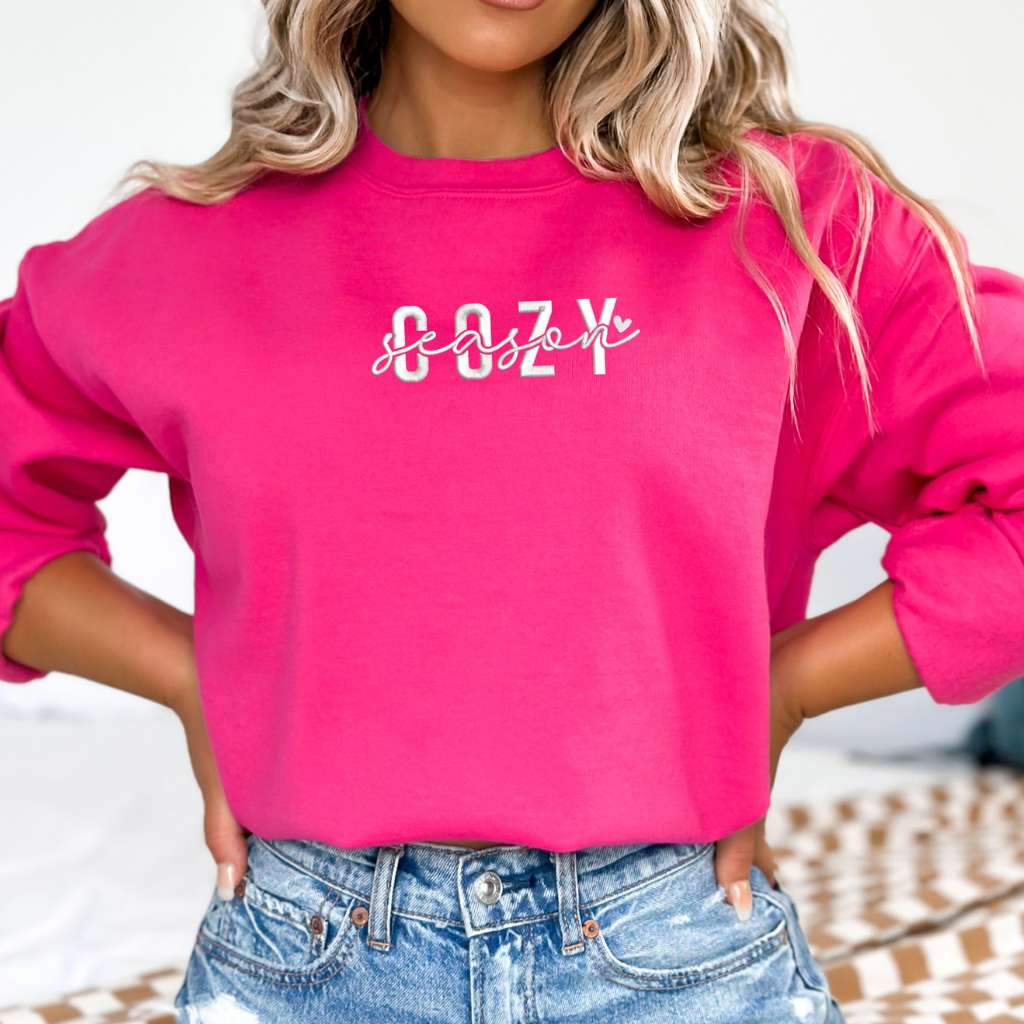 Female wearing a hot pink crewneck sweatshirt embroidered with Cozy Season - DSY Lifestyle