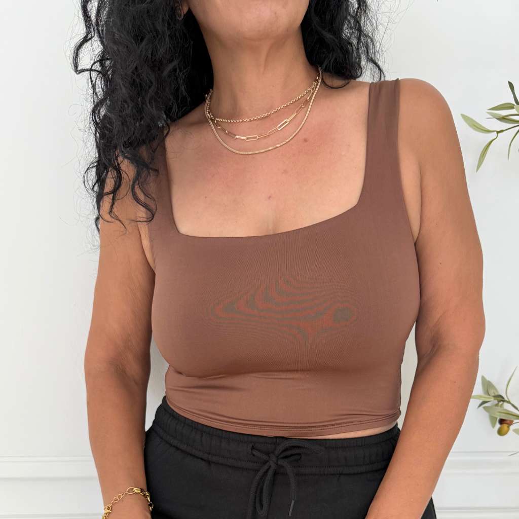 Woman wearing a brown square neck crop top with black drawstring pants and gold layered necklaces