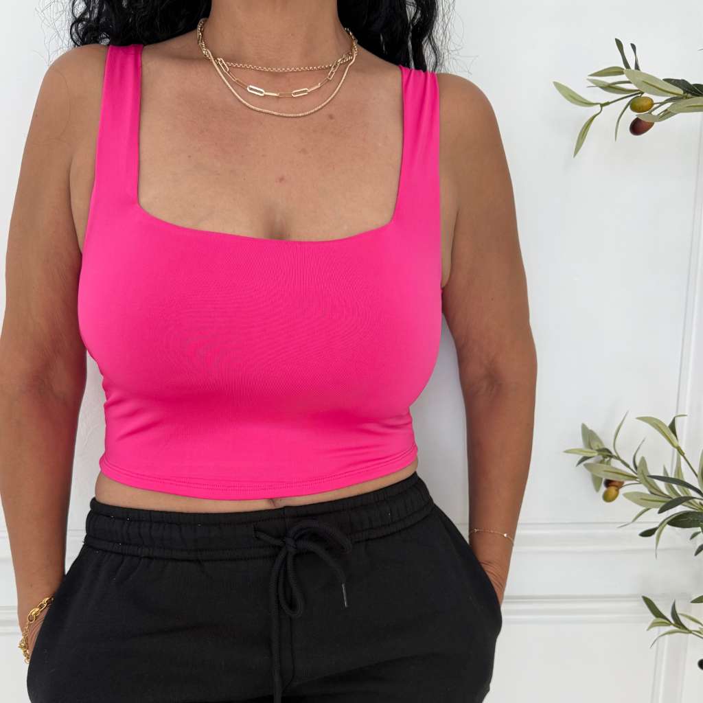 Vibrant pink square neck stretch tank on a woman with black joggers and layered gold necklaces.

