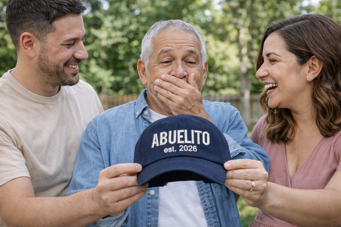Couple presenting handsome man with Navy Blue Abuelito Est. 2026 Baseball Hat featuring clean white embroidery on a classic navy dad cap; a thoughtful 2026 pregnancy announcement gift for a new grandpa by DSY Lifestyle.
