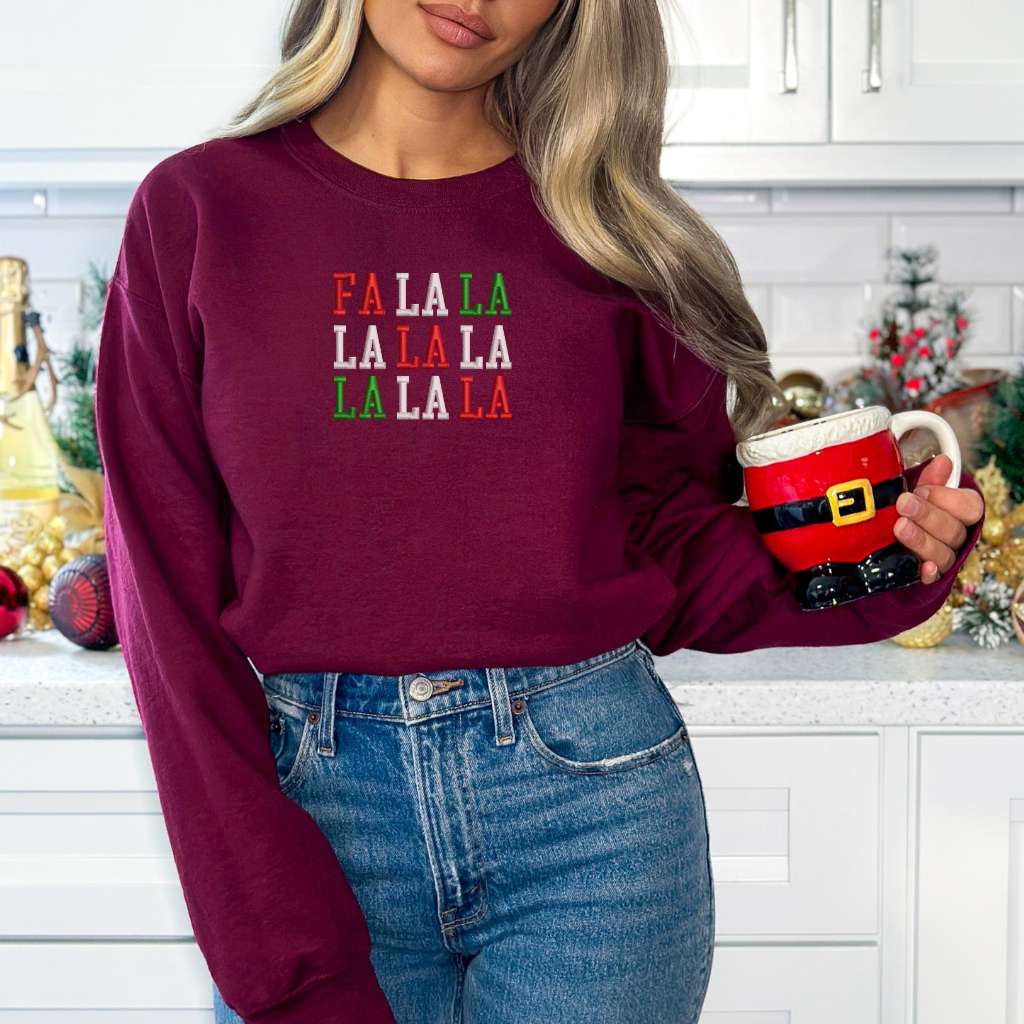 Female wearing a burgundy sweatshirt embroidered with Fa la la in Christmas Colors - DSY Lifestyle