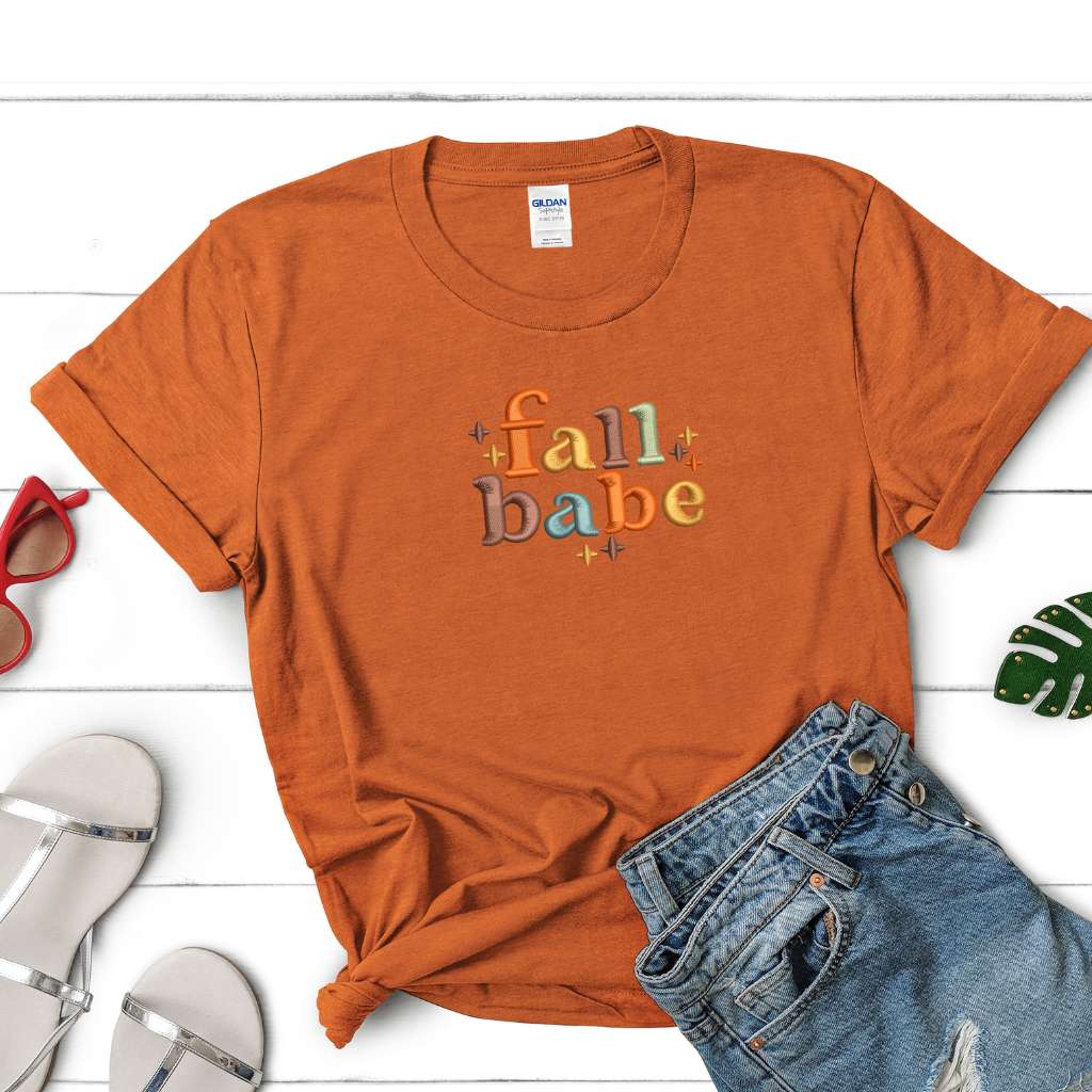 Female wearing a burnt orange t-shirt embroidered with Fall Babe - DSY Lifestyle
