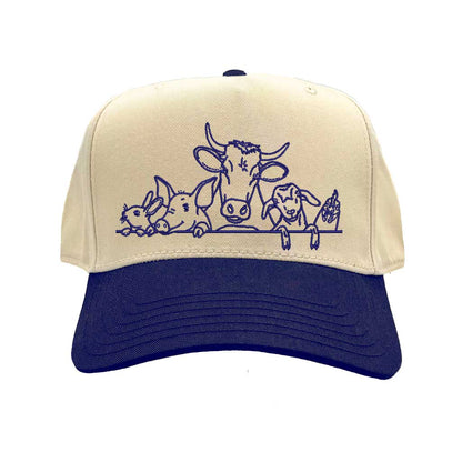 Natural Navy Blue DSY Lifestyle two-tone baseball hat with a natural crown and  contrasting bill, featuring an embroidered graphic of a cow, pig, and rooster family. - DSY Lifestyle