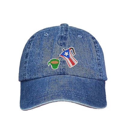 A light denim embroidered hat featuring a detailed design of a greca (stovetop coffee maker) pouring coffee into a nostalgic green butter cup, symbolizing Puerto Rican coffee culture. The greca has the Puerto Rican flag inside it, representing heritage and tradition - DSY Lifestyle.