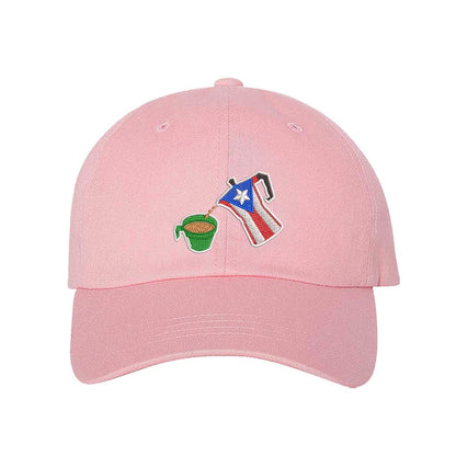 A pink embroidered hat featuring a detailed design of a greca (stovetop coffee maker) pouring coffee into a nostalgic green butter cup, symbolizing Puerto Rican coffee culture. The greca has the Puerto Rican flag inside it, representing heritage and tradition - DSY Lifestyle